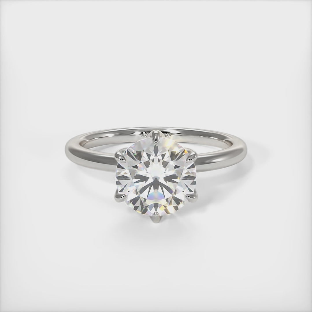 A beautiful engagement ring in gold or platinum that includes a 1ct, 2ct, 3ct round Colorless Moissanite set into the 6 prongs setting. This solitaire ring is designed to allow the wedding band to sit close and flush with the engagement ring because the center stone sits directly above the band./AGI Design