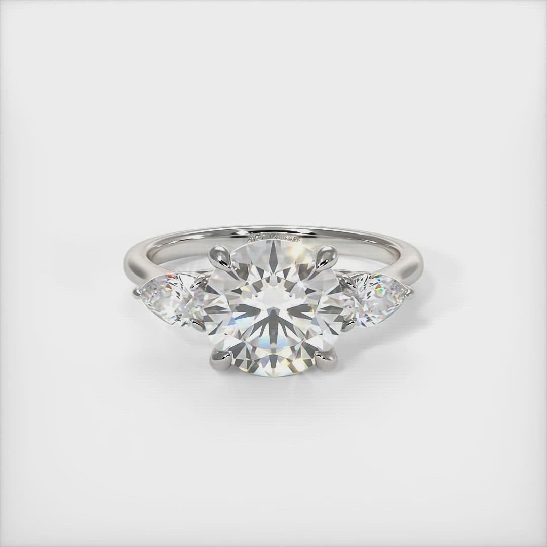 Leah Round Moissanite with Pear Shape Lab Diamonds Engagement Ring - AGI Design/This elegant solid gold or platinum engagement ring features a round moissanite and pear-shaped lab-created diamonds. This 1ct, 2ct three stone ring is designed to allow the wedding band to sit close and flush with the engagement ring.