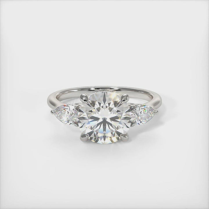 Leah Round Moissanite with Pear Shape Lab Diamonds Engagement Ring - AGI Design/This elegant solid gold or platinum engagement ring features a round moissanite and pear-shaped lab-created diamonds. This 1ct, 2ct three stone ring is designed to allow the wedding band to sit close and flush with the engagement ring.