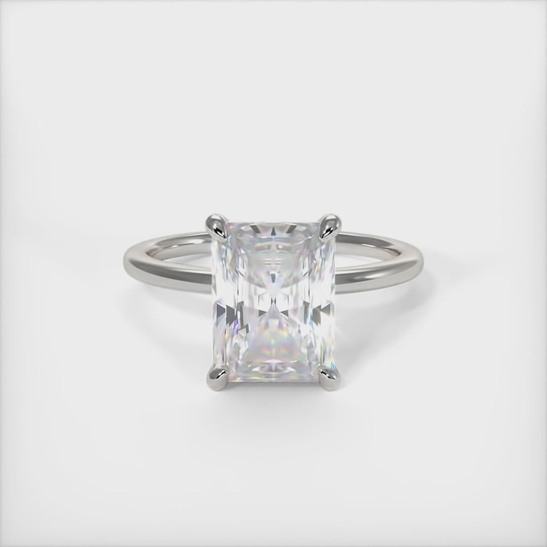 A beautiful Engagement ring in gold or platinum that includes a 1ct, 2ct Radiant Moissanite set into the 4 prongs hidden halo setting. The band and the halo are covered with Lab-created diamonds. This  solitaire ring is designed to allow the wedding band to sit close and flush with the engagement ring because the center stone sits directly above the band. AGI Design