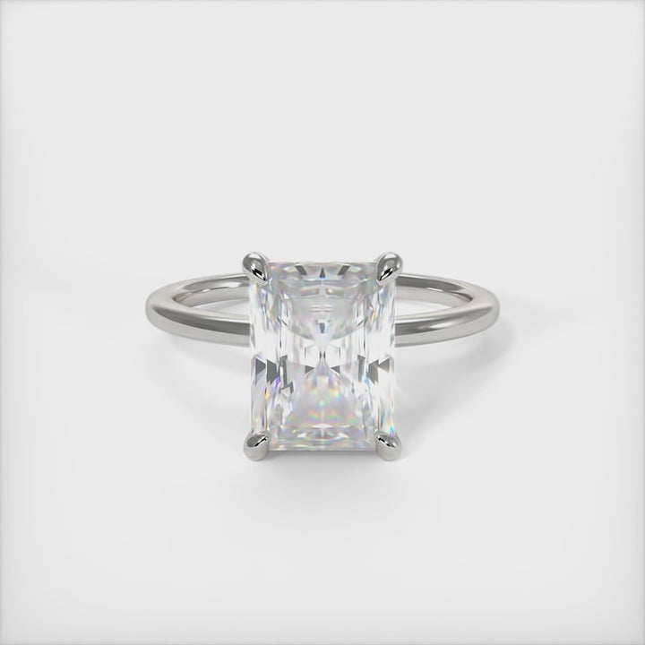 A beautiful Engagement ring in gold or platinum that includes a 1ct, 2ct Radiant Moissanite set into the 4 prongs hidden halo setting. The band and the halo are covered with Lab-created diamonds. This  solitaire ring is designed to allow the wedding band to sit close and flush with the engagement ring because the center stone sits directly above the band. AGI Design