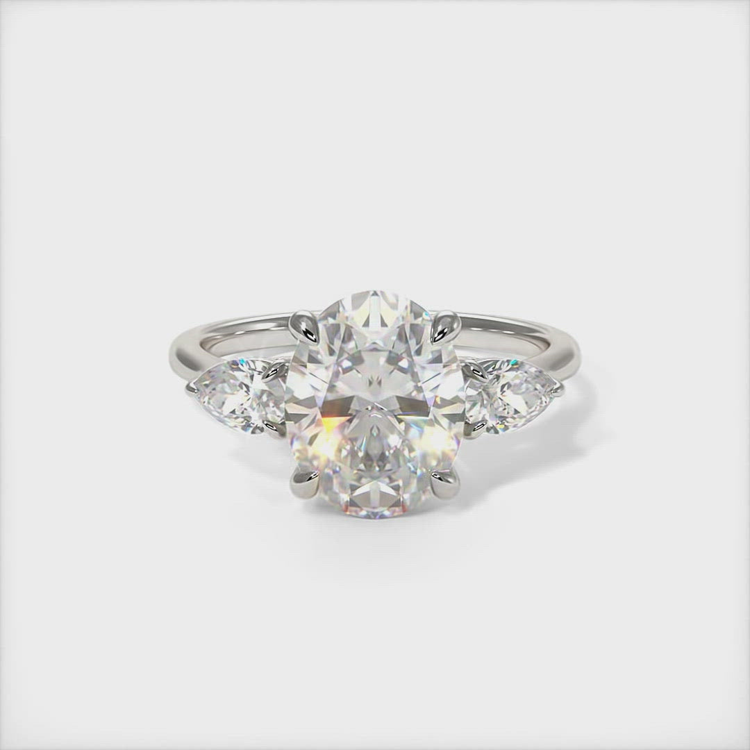Leah Oval Moissanite with Pear Shape Lab Diamonds Engagement Ring - AGI Design/This elegant solid gold or platinum engagement ring features a oval moissanite and pear-shaped lab-created diamonds. This 1ct, 2ct three stone ring is designed to allow the wedding band to sit close and flush with the engagement ring.