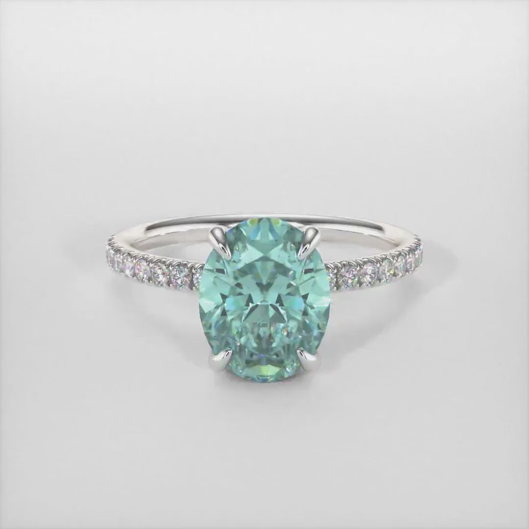 Abigail Oval Aqua Teal Moissanite Engagement Ring/ AGI Design. A beautiful engagement ring in gold or platinum that includes an Aqua-Teal Oval Moissanite set into the 4 prongs hidden halo setting. The band and the halo are covered with lab-created diamonds. This solitaire ring is designed to allow the wedding band to sit  flush with the engagement ring because the center stone sits directly above the band.