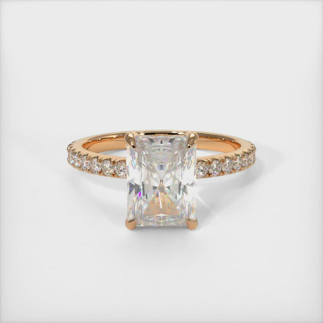 A beautiful Engagement ring in gold or platinum that includes a Radiant Moissanite set into the 4 prongs hidden halo setting. The band and the halo are covered with Lab-created diamonds.  This ring is designed to allow the wedding band to sit close and flush with the engagement ring because the center stone sits directly above the band. 