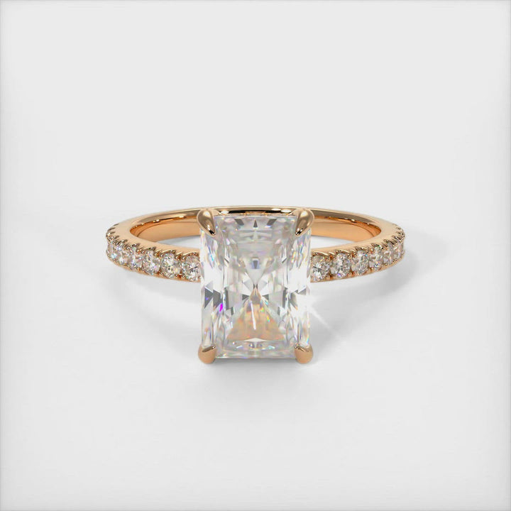 A beautiful Engagement ring in gold or platinum that includes a Radiant Moissanite set into the 4 prongs hidden halo setting. The band and the halo are covered with Lab-created diamonds.  This ring is designed to allow the wedding band to sit close and flush with the engagement ring because the center stone sits directly above the band. 