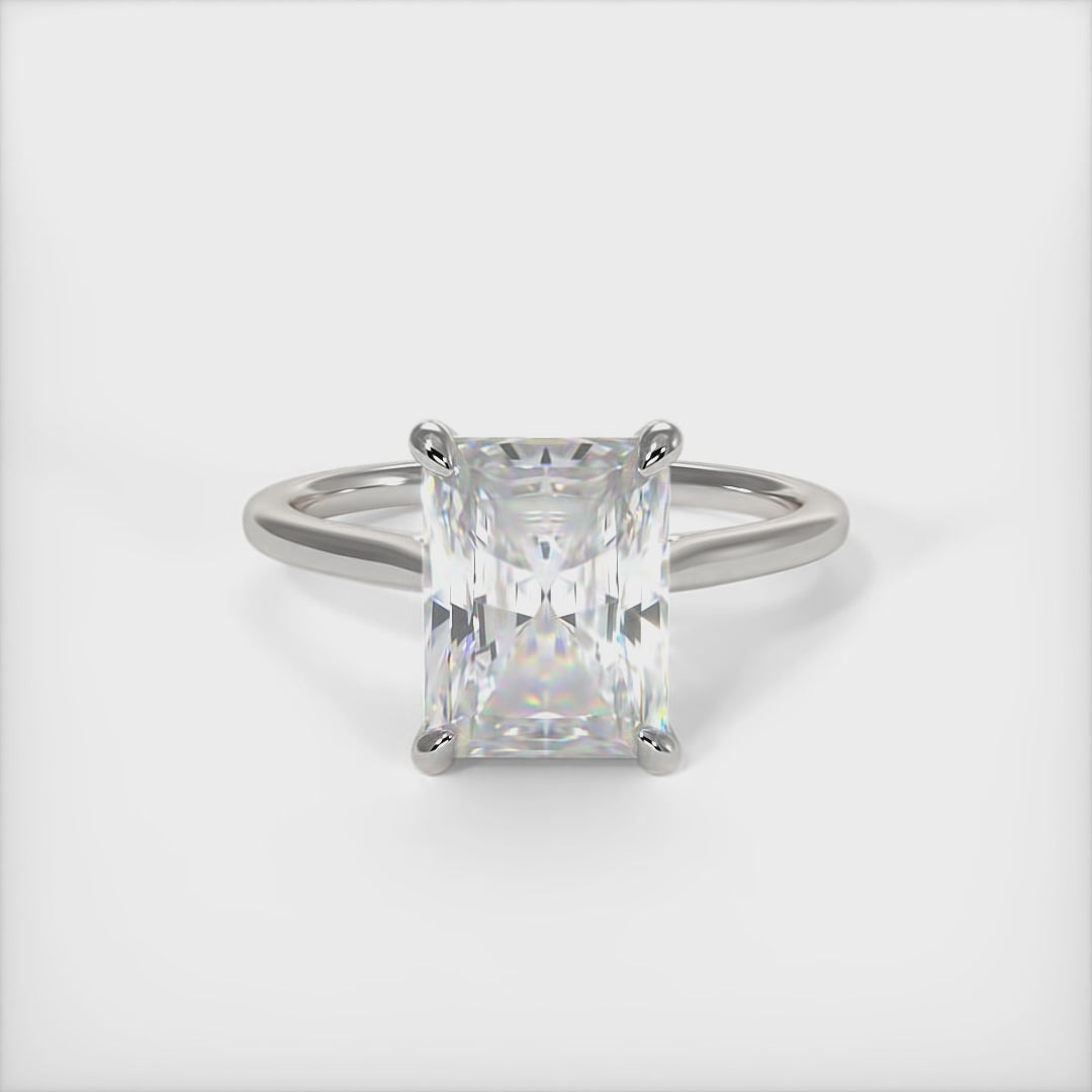 A beautiful Engagement ring in gold or platinum that includes a 1ct, 2ct Radiant Moissanite set into the 4 prongs hidden halo setting. The band and the halo are covered with Lab-created diamonds. This  solitaire ring is designed to allow the wedding band to sit close and flush with the engagement ring because the center stone sits directly above the band. AGI Design