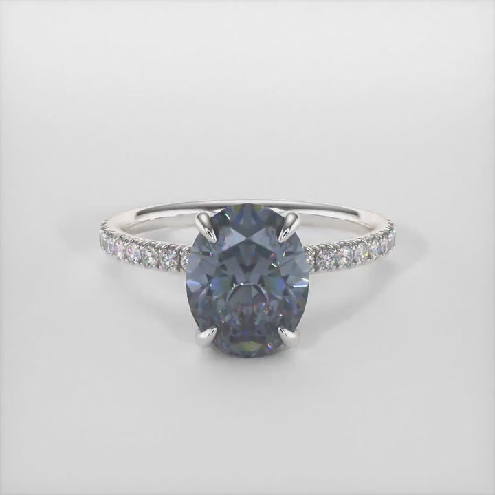 Abigail Oval Dark Gray Moissanite Engagement Ring/ AGI Design. A beautiful engagement ring in gold or platinum that includes a gray Oval Moissanite set into the 4 prongs hidden halo setting. The band and the halo are covered with lab-created diamonds. This solitaire ring is designed to allow the wedding band to sit  flush with the engagement ring because the center stone sits directly above the band.