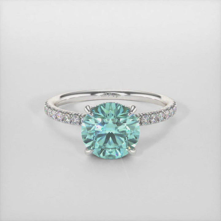 This incredible engagement ring features a round Aqua-teal Moissanite surrounded by a hidden halo of round Lab-Created brilliant-cut diamonds that make their way down the ring’s shank. This ring is designed to allow the wedding band to sit close and flush with the engagement ring. AGI Design