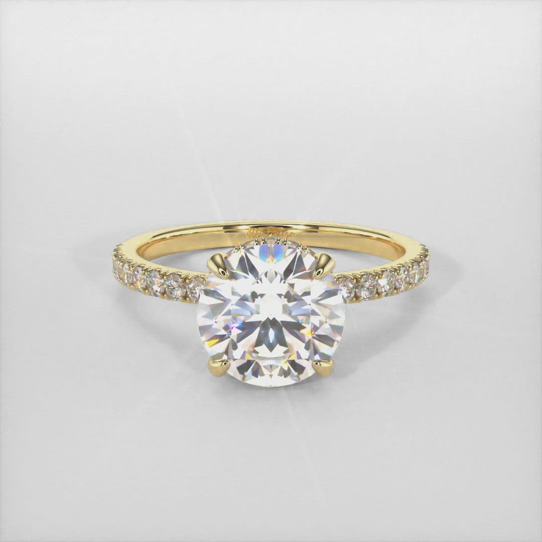 The delicate engagement ring in gold or platinum  features a hidden halo and a round colorless moissanite as the center stone. High-quality lab-created diamonds cover the band and the halo of this solitaire ring. 