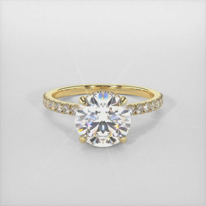 The delicate engagement ring in gold or platinum  features a hidden halo and a round colorless moissanite as the center stone. High-quality lab-created diamonds cover the band and the halo of this solitaire ring. 