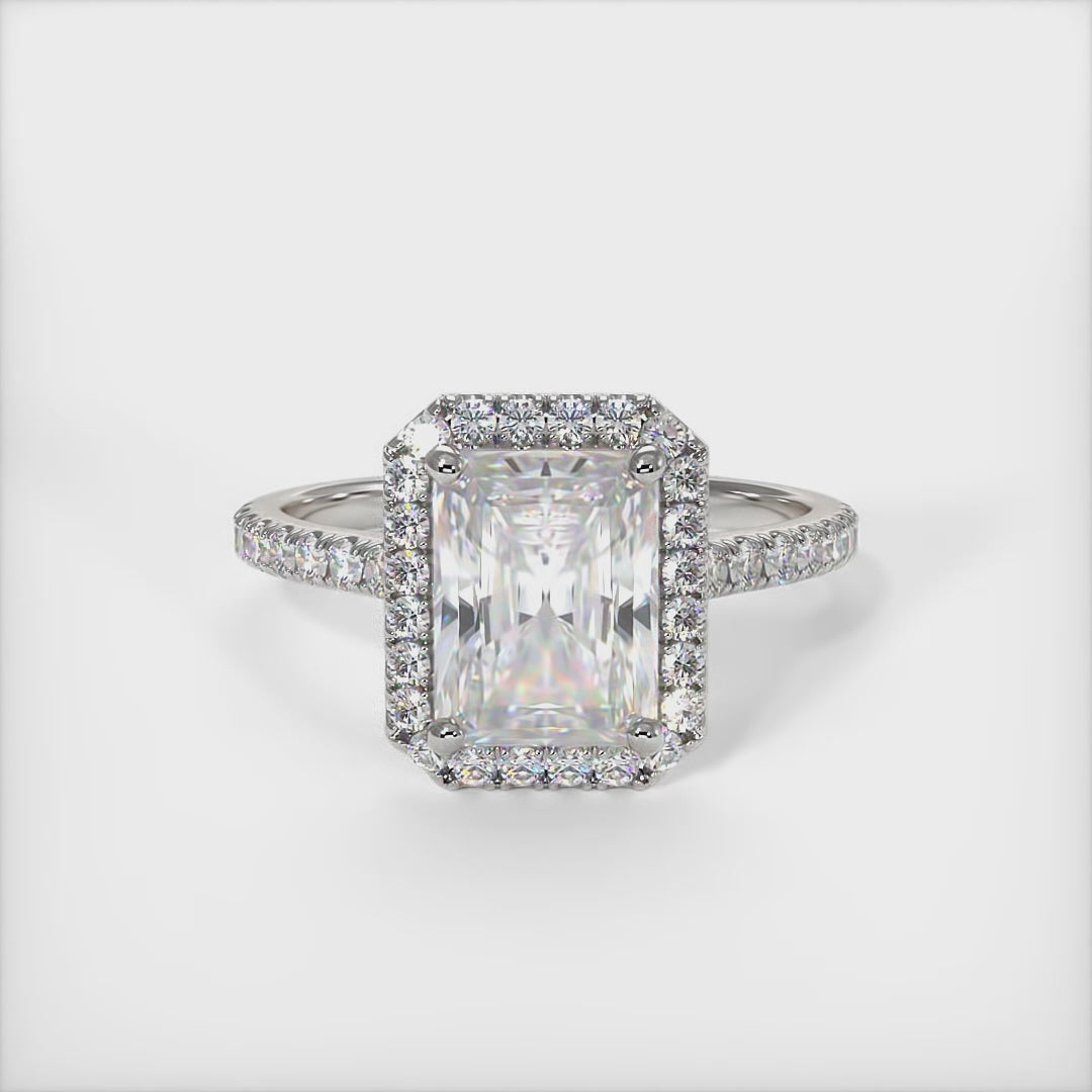 A beautiful Engagement ring in gold or platinum that includes a 1ct, 2ct Radiant Moissanite set into the 4 prongs halo setting. The band and the halo are covered with Lab-created diamonds. This  solitaire ring is designed to allow the wedding band to sit close and flush with the engagement ring because the center stone sits directly above the band. /AGI Design