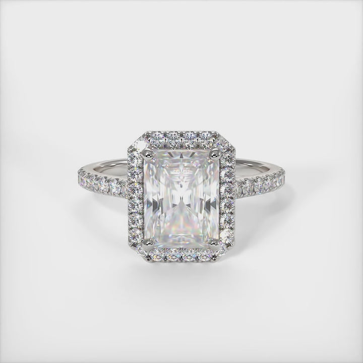 A beautiful Engagement ring in gold or platinum that includes a 1ct, 2ct Radiant Moissanite set into the 4 prongs halo setting. The band and the halo are covered with Lab-created diamonds. This  solitaire ring is designed to allow the wedding band to sit close and flush with the engagement ring because the center stone sits directly above the band. /AGI Design