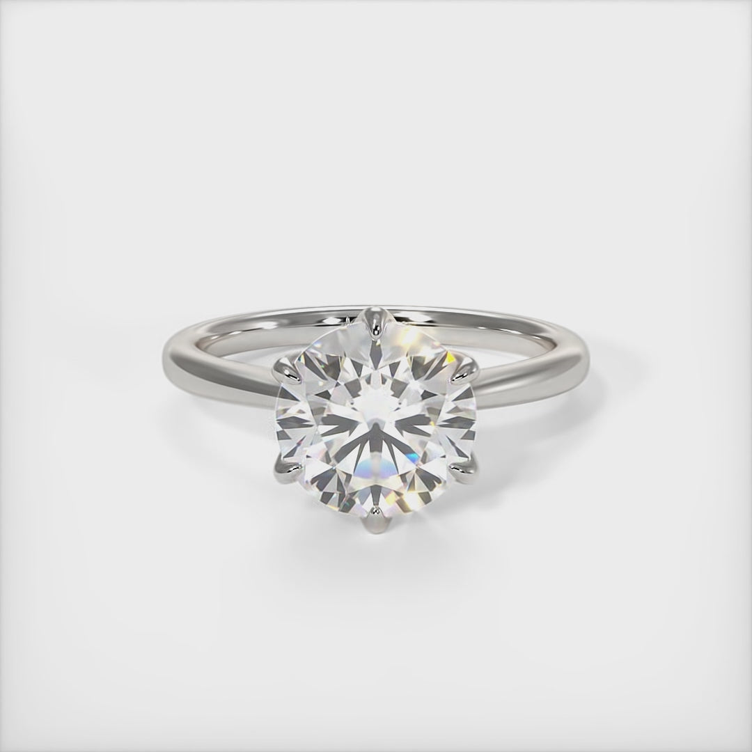 A beautiful engagement ring in gold or platinum that includes a  1ct,  2ct, 3ct round Colorless Moissanite set into the 6 prongs setting. This solitaire ring is designed to allow the wedding band to sit close and flush with the engagement ring because the center stone sits directly above the band./AGI Design